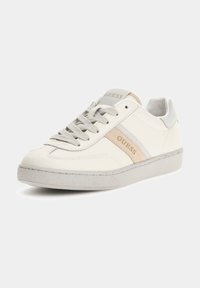 Sneakers bianchi in pelle con accenti beige, una suola intermedia testurizzata e design con lacci. Presentano un logo "Guess" sulla linguetta e sulla striscia laterale.
