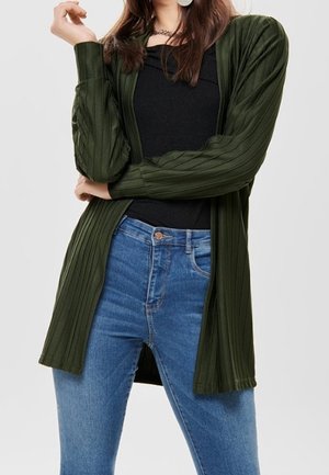 Dark green ribbed cardigan with long sleeves and an open front, paired with a black top and blue jeans. Smooth texture and relaxed fit.