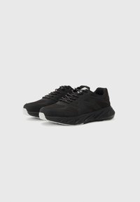 Black athletic shoes with a textured upper, featuring mesh panels, reflective laces, and a cushioned sole with a white accent.