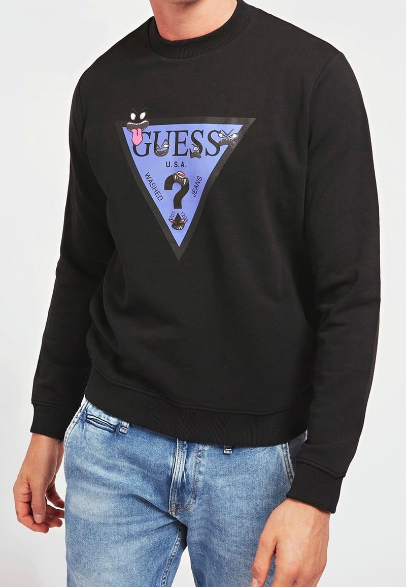 Sudadera negra con un gráfico triangular azul. Presenta logotipos coloridos, texto y diseños faciales en un estilo juguetón. Puños y dobladillo acanalados.