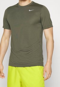 T-shirt atletico a maniche corte verde oliva di Nike con collo rotondo e logo discreto. Realizzato in tessuto liscio e leggero con una forma aderente.