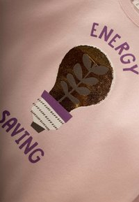 Sudadera de color rosa claro que presenta un gráfico de una bombilla con un diseño metálico en dorado y gris, rodeada por el texto "AHORRO DE ENERGÍA."