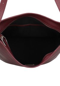 Bordeauxrode leren handtas met een gestructureerd oppervlak, ritssluiting en zwarte stoffen voering. Ruime binnenkant zonder zichtbare vakken.