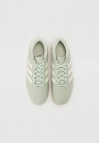 Ljusgröna sportskor med tre vita ränder, strukturerad läderöverdel, rund tå och platta snören. Designade för komfort och prestanda.
