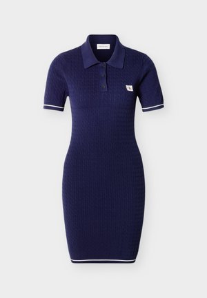 Vestido polo de punto en azul marino con mangas cortas, cuello con botones, ribete blanco en los puños de las mangas y el dobladillo, y pequeño parche con logo en el pecho.