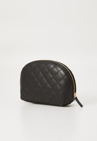 Funda de cuero acolchada negra con forma redondeada, cuenta con una cremallera dorada y un pequeño asa lateral para un fácil transporte.