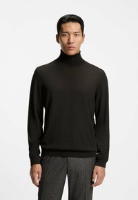 Czarny sweter z golfem wykonany z miękkiego dzianinowego materiału, z długimi rękawami i prążkowanymi mankietami, zestawiony z szarymi spodniami w wzory.