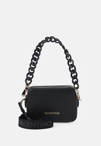 Czarna skórzana torebka z teksturowym wykończeniem, z masywnym uchwytem w formie łańcucha oraz paskiem z logo. Złote akcenty metalowe. Prostokątny kształt.
