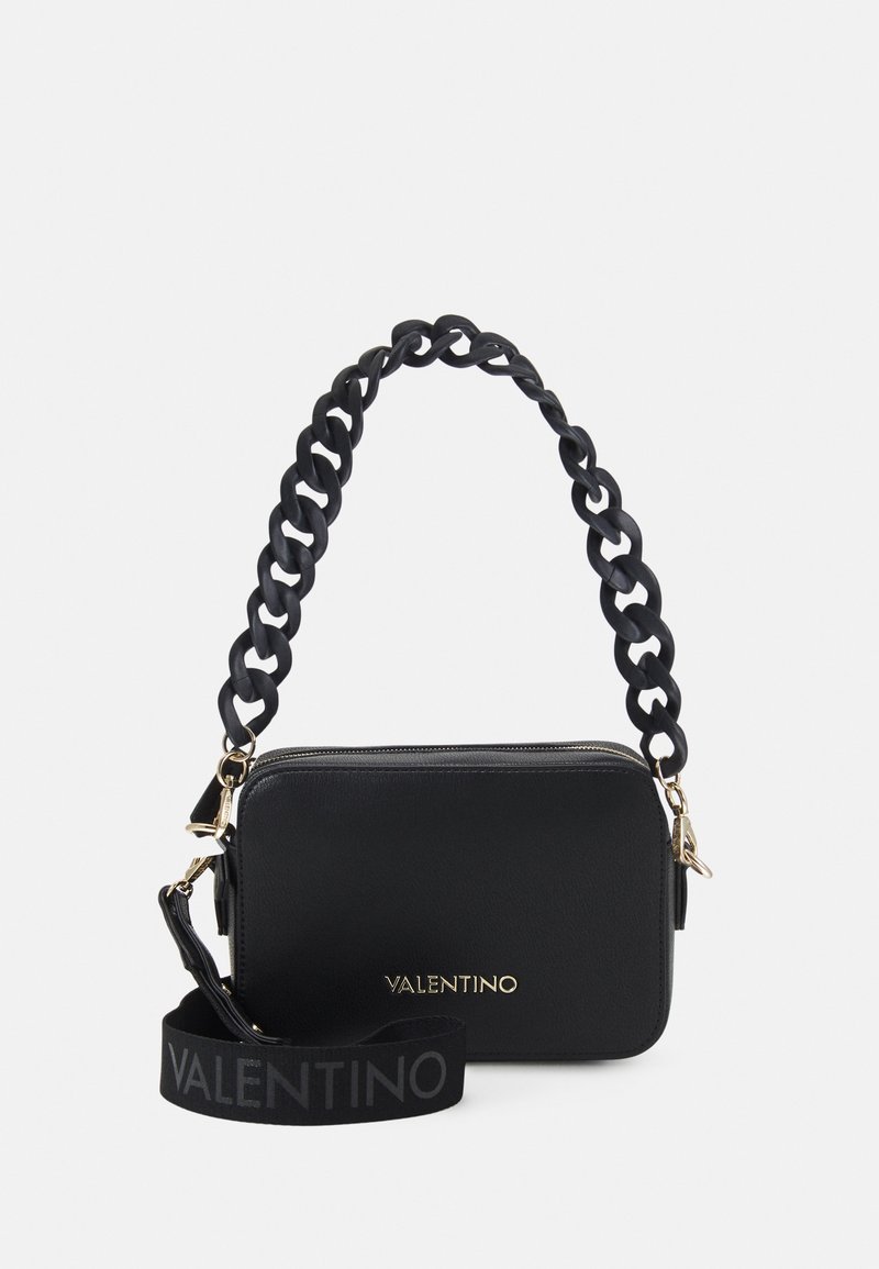 Czarna skórzana torebka z teksturowym wykończeniem, z masywnym uchwytem w formie łańcucha oraz paskiem z logo. Złote akcenty metalowe. Prostokątny kształt.