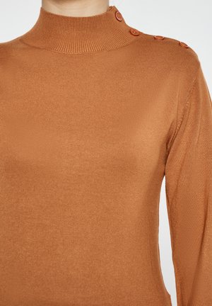 Sweter w kolorze rdzy z wysokim prążkowanym dekoltem, z czterema ozdobnymi guzikami na jednym ramieniu oraz gładką, elastyczną teksturą.