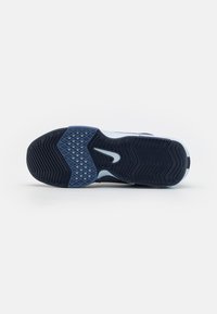 Semelle d’une chaussure de sport bleu foncé et bleu clair avec des motifs de grip texturés et un logo blanc en forme de swoosh au centre.