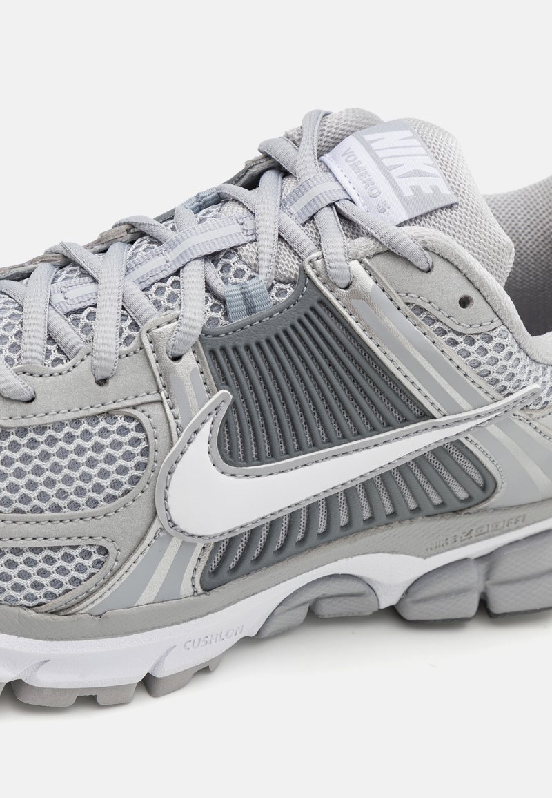 Zapatilla deportiva gris con parte superior de malla, suela de goma, logo de Nike en blanco y acentos texturizados para la transpirabilidad y flexibilidad.