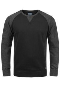 Sudadera negra con mangas raglán gris oscuro, cuello redondo, puños y dobladillo acanalados. Material suave con un diseño minimalista y sin patrones.