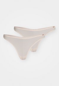 Twee paar beige stringonderbroeken van een gladde, rekbare stof. Kenmerken zijn dunne elastische banden en een minimaal dekkend ontwerp.