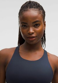 Sötétkék sportfelső magas nyakkal és ujjtalan dizájnnal. Simaságú szövettextúra, minimalista stílus, és nincsenek látható minták vagy kiegészítő elemek.