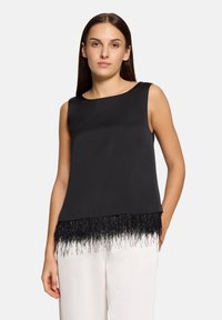 Czarny bezrękawnik z gładką górną częścią i teksturowanymi frędzlami przy dolnym brzegu. Wykonany z lekkiego materiału.