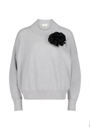 Lys grå strikket sweatshirt med høj krave og en sort stofblomst som accent på venstre side. Har ribbede manchetter og kant.