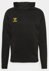 Zwarte hoodie met een ritszak aan de zijkant, voorzien van een geel logo op de borst en patronen op de mouwen. Zachte stoftextuur.