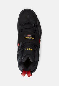 Černá teniska kombinuje semišový a síťovaný materiál. Obsahuje šněrování, polstrovaný límec, červené akcenty a nášivku s logem.