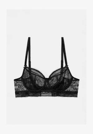 Soutien-gorge en dentelle noire avec armatures, bonnets transparents et bretelles réglables. Des finitions délicates et des bords en forme de vagues rehaussent le design.