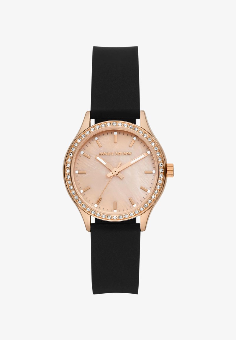 Montre ronde en or rose avec lunette sertie de cristaux, cadran rose clair, index et aiguilles dorés, et bracelet en silicone noir.