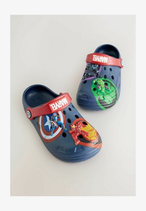 Zoccoli blu con cinturino rosso decorati con disegni di supereroi Marvel. Include figure decorative di Iron Man, Captain America e Hulk.