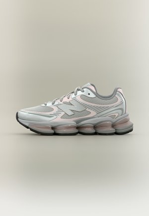 Chaussure de course New Balance grise et rose avec semelle segmentée amortie et tige en mesh sur fond neutre.