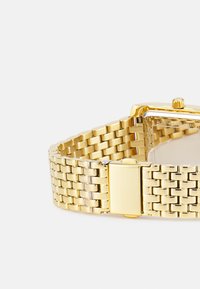 Goldfarbene Edelstahl-Uhr mit rechteckigem Zifferblatt, Maschenarmband-Design und polierter Oberfläche. Verfügt über einen Klappverschluss.