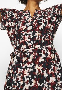 Vestido de estampado floral en tonos rojos, negros y crema. Presenta un escote en V, mangas amplias y un cinturón atado en la cintura para un ajuste ajustable.