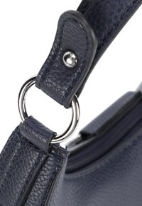 Dunkelblauer Lederhandtaschenriemen mit strukturierter Oberfläche, silberner Metallbeschläge und einem runden Ringbefestigungsdetail.