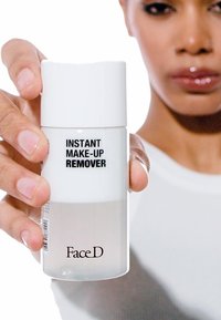 Bottiglia di plastica trasparente con un tappo bianco. L'etichetta riporta "STRUCCANTE ISTANTANEO" e "FaceD" in carattere nero. Il contenuto è un liquido chiaro.