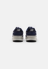 Navy blue athletic shoes featuring a mesh and suede combination, with a cushioned sole and a silver logo detail on the heel.