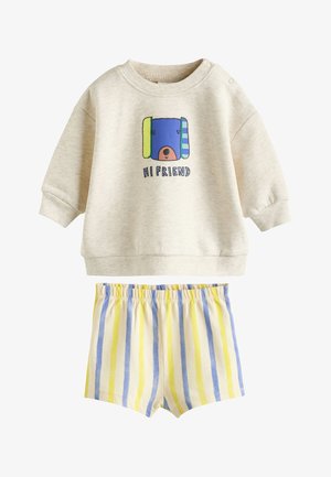 Felpa beige a maniche lunghe per neonati con grafica di un orso e scritta "HI FRIEND" abbinata a pantaloncini a righe gialle e blu con elastico in vita.