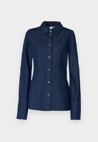 Tumman denim-paitajakku, jossa on kärkipontto, pitkät hihat ja kuusi etunappia. Tässä on näkyvää ompelua ja lievää muotoilua vyötäröllä.