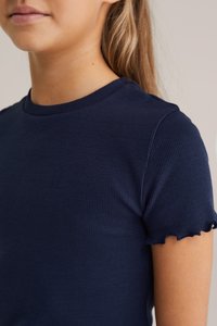 Tmavě modré žebrované tričko s krátkým rukávem a vlnkovým lemem. Měkká textura a priléhavý design zdůrazňující výstřih a oblast ramen.
