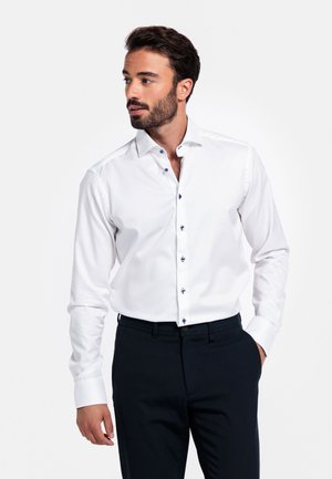 Witte dress shirt met een slim fit, voorzien van een spread collar, donkere blauwe knopen en lange mouwen, gecombineerd met donkere broeken.