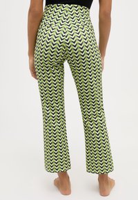 Högmidjade utsvängda byxor med ett zigzag-mönster i grönt, svart och vitt, med en mjuk textur och två bakfickor.