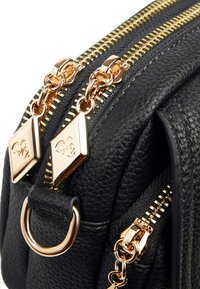 Borsa a tracolla in pelle nera con texture, zip dorate, hardware a forma di diamante e dettaglio a cerchio in metallo.