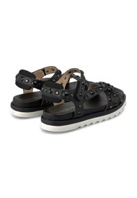 Sandalias negras con múltiples correas, pernos decorativos redondos y una suela de goma blanca. Material de cuero suave y plantilla acolchada.