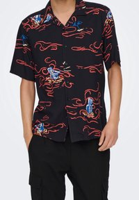 Zwarte t-shirt met korte mouwen, versierd met kleurrijke golfpatronen, blauwe paraplu's en rode spiralen; lichte stof met een relaxte pasvorm.