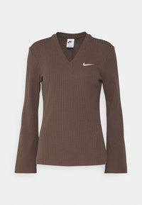 Haut marron à manches longues à côtes, avec un décolleté en V et un petit logo Nike blanc sur la poitrine gauche. Texture douce, design ajusté.