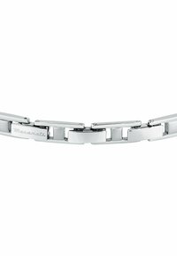 Armband av rostfritt stål med länkar som låser i varandra, polerad yta, elegant design och ingraverad logotyp. Silverfärg med minimal detaljering.