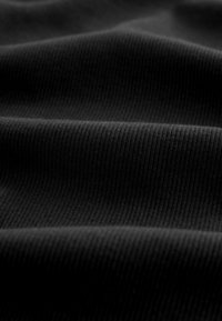 Primo piano di tessuto nero a coste con pieghe morbide e linee di trama visibili.