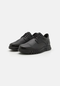 Black leather lace-up shoes with a smooth finish, rounded toe, and textured rubber sole featuring a zigzag pattern.