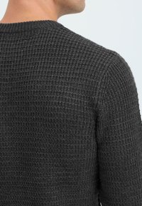 Mørkegrå vaffelstrikket sweater med rund halsudskæring og tekstureret stof, med en tætsiddende pasform og ribbede manchetter.