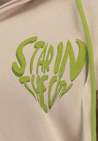 Tessuto beige con la scritta grafica verde "STAR IN THE CITY", con una finitura testurizzata e cuciture a contrasto lungo i bordi.