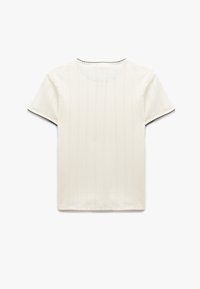 Top blanco de manga corta con un patrón acanalado texturizado, borde negro festoneado en el escote y las mangas, y un corte relajado.
