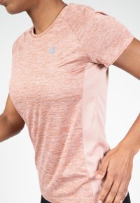 Lichtroze sportt-shirt van gestructureerde, vochtafvoerende stof. Heeft korte mouwen en een contrasterend zijpaneel in een effen kleur.