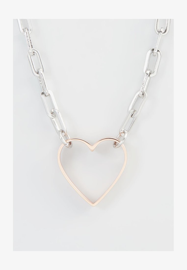 Zilveren ketting met grote ovale schakels, met een dunne, open rosegouden hartkwast in het midden. Minimalistisch ontwerp.