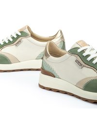 Zapatillas ligeras de cuero en crema, verde y dorado con costuras decorativas, cordones blancos y una suela de goma texturizada.